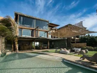 Nowoczesny dom przy plaży z dużymi oknami, basenem i palmami - idealny na wyjazdy kitesurfingowe z KiteAway.