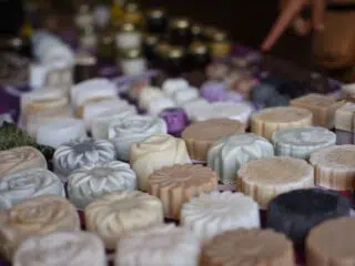 Kolorowe mydełka na targu, jak na wakacjach z kitesurfingiem z KiteAway; tło z rozmytymi słoikami i akcesoriami.