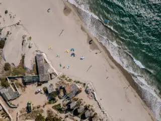 Plaża z palmami i kolorowymi latawcami, uczestnicy wyjazdu KiteAway. Idealny kite spot na wakacje z kitesurfingiem.
