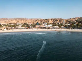 Widok z lotu ptaka na miasteczko i szeroką plażę - idealny spot na wyjazdy kitesurfingowe z KiteAway.pl; fale, słoneczne niebo.