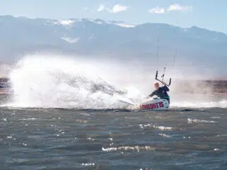 Kitesurfer sunący po wzburzonej wodzie przy górach - idealny kite trip KiteAway, wakacje z kitesurfingiem na najlepszych spotach.