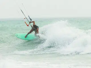 Kitesurfer na turkusowej pustyni manewruje po fali - dynamiczny kurs kitesurfingu z KiteAway, niezapomniane wyjazdy kitesurfingowe.